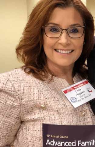A woman with glasses and a name tag.